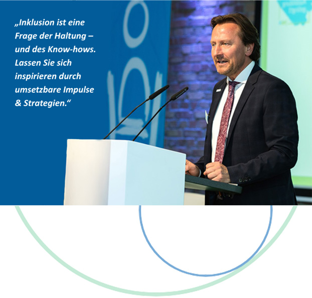 Man sieht Olaf Guttzeit von der Seite. Er trägt einen dunklen Anzug, weißes Hemd und Krawatte. Seine Fäuste liegen leicht geballt auf einem Pult mit zwei Mikrofonen, in die er engagiert spricht. Daneben steht: „Inklusion ist eine Frage der Haltung – und des Know-hows. Lassen Sie sich inspirieren durch umsetzbare Impulse & Strategien.“